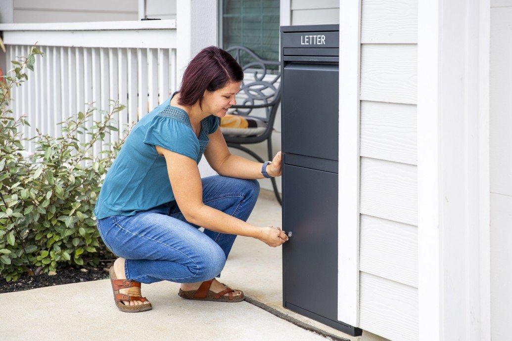 Experience convenience with Feliluke's oversized black mail and package locker, securely installed at the porch. Watch as a woman, dressed in a stylish blue top and jeans, joyfully opens the locker using a key.