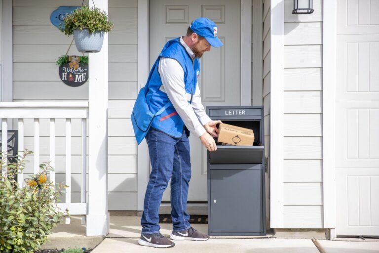 A deliveryman wearing a blue uniform is placing packages in front of a black Feliluke delivery locker at a household.