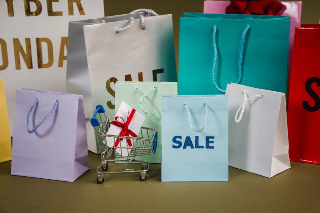 a lot of paper bags printed wiht sale! There is a small cart with a white gift box among bags.