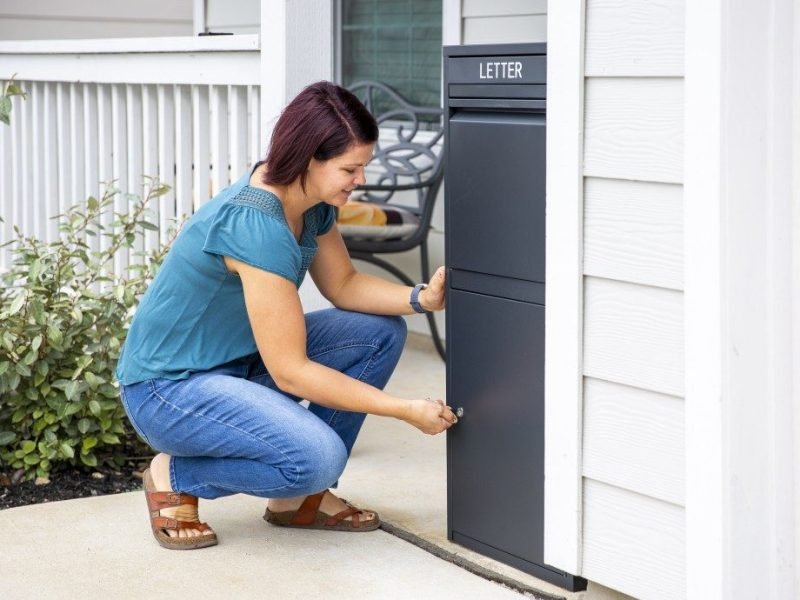 Experience convenience with Feliluke's oversized black mail and package locker, securely installed at the porch. Watch as a woman, dressed in a stylish blue top and jeans, joyfully opens the locker using a key.